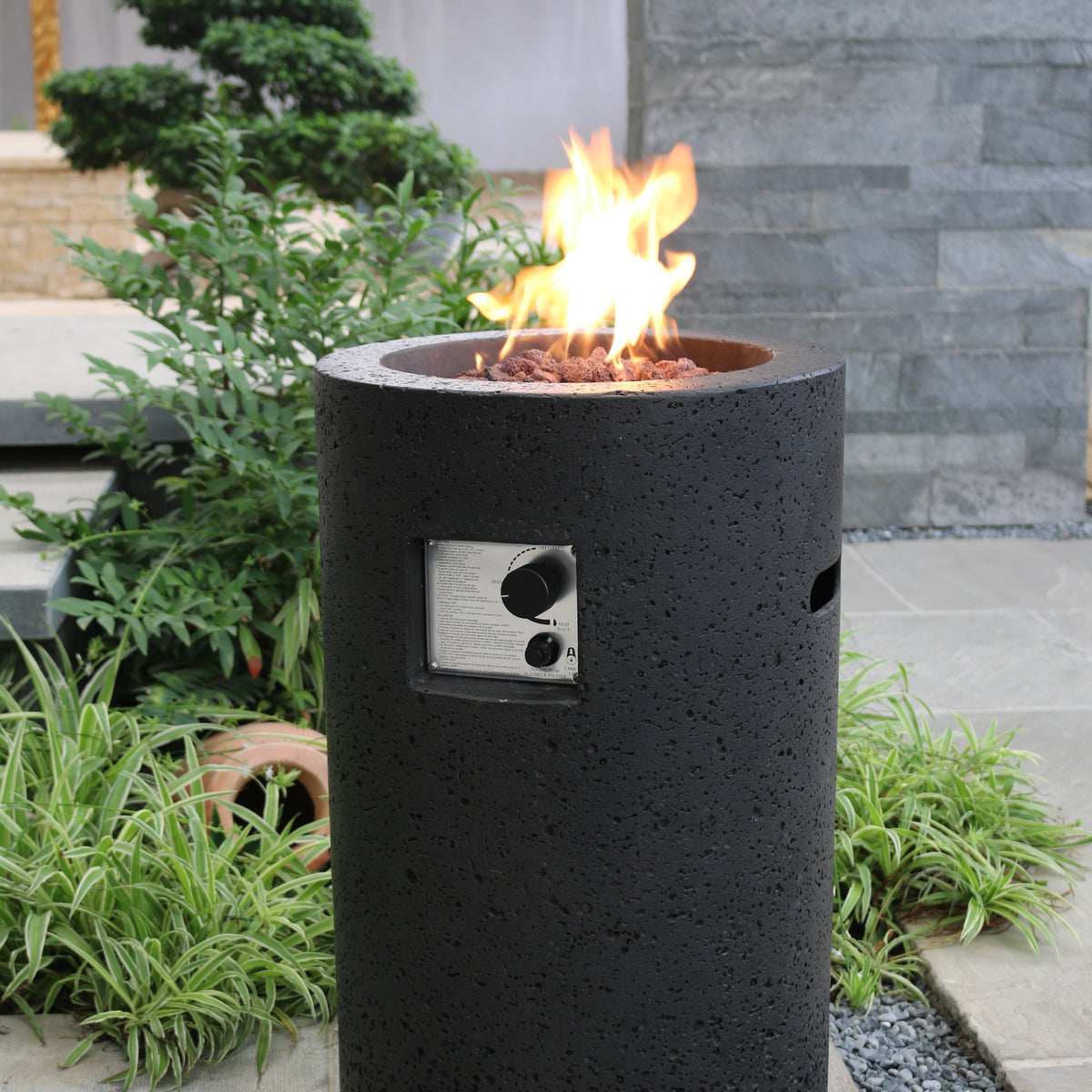 Modeno Lava Tube Propane Fire Pit - Lush Garden Patio with Natural Stone Wall - Elementi Fires
